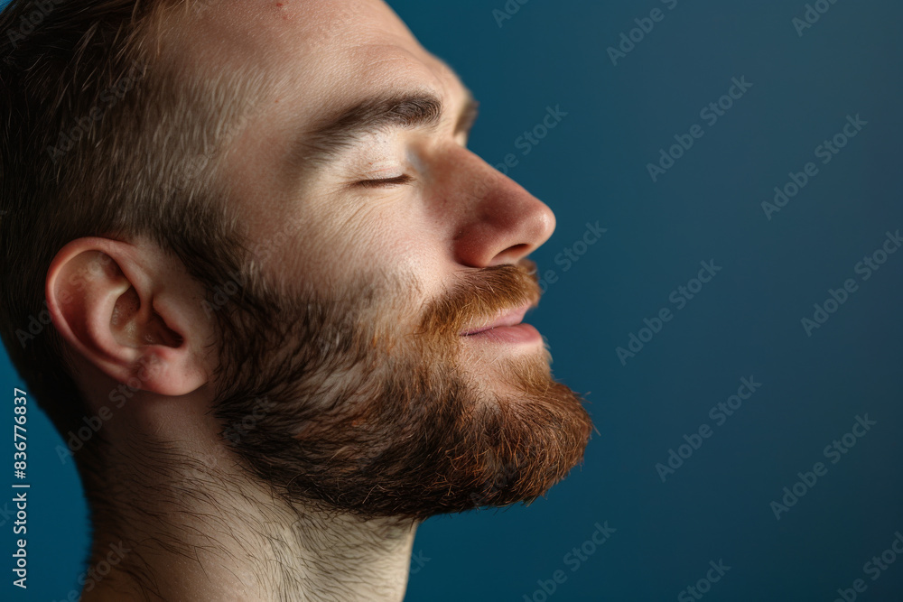 Obraz premium A close up of a man with beard and closed eyes looking to a side
