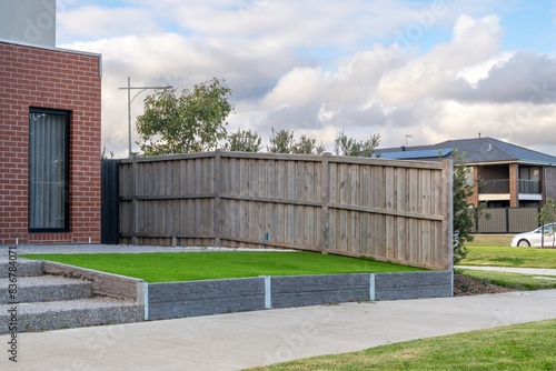 Wallpaper Mural A neatly maintained artificial grass lawn bordered by a low and wooden retaining wall in the front garden with the fence of a suburban home. Landscaping project of a small yard. Torontodigital.ca
