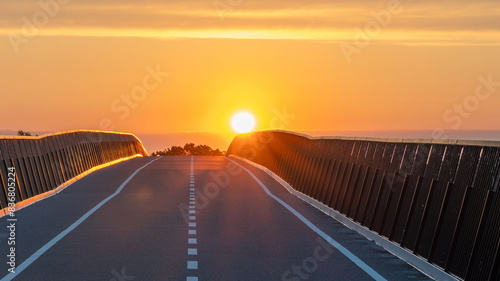 sunrise on a bridge, some clouds and a orange and yellow sky