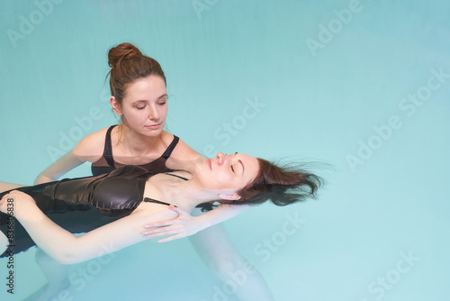 Two woman in pool. Watsu. Blue water rehabilitation massage. Aqua therapy exercise. Physio medical fitness. Sport spa relax. Swim gym class. Adult rehab physiotherapy photo