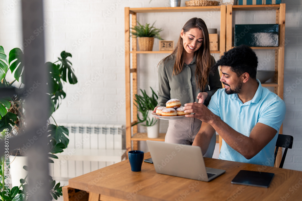 A businessman in his home office taking a break to eat a donut with his wife. A businessman in his home office taking a break to eat a donut with his wife.