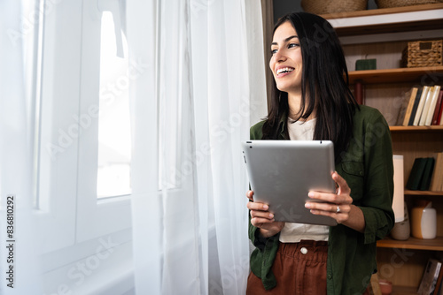 Attractive woman working on a digital tablet in a home office. Businesswoman small company owner work online from her apartment. Independent freelance graphic designer female enjoying freedom and job.