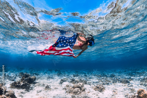 Freediver swims in tropical sea with United States flag. Independence day concept.