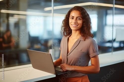 smiling female entrepreneur with laptop standing in office