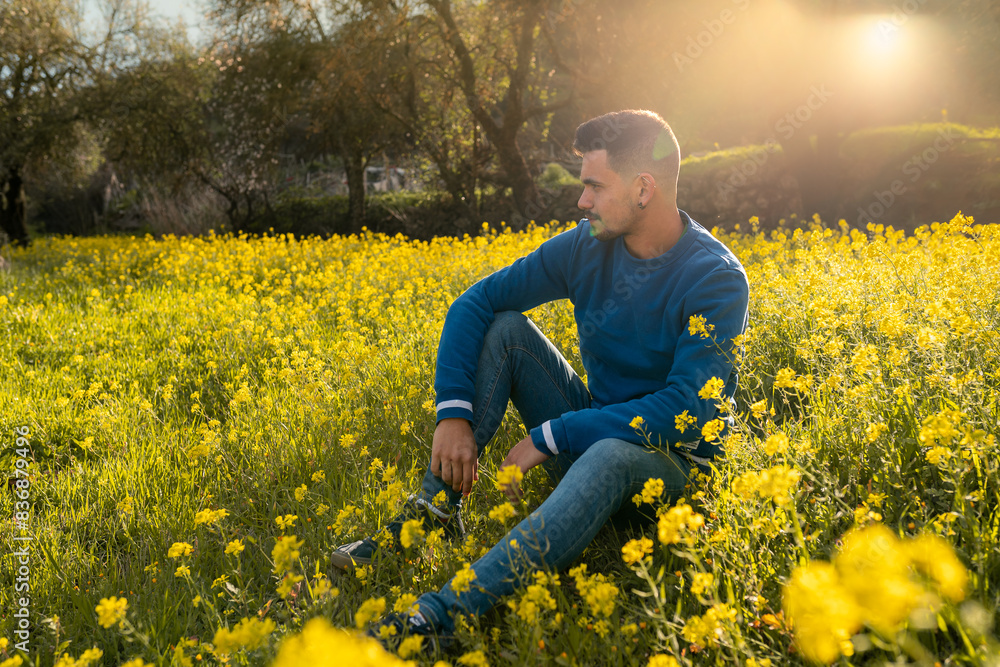 young man in a field of yellow wildflowers at sunset young man in a field of yellow wildflowers at sunset