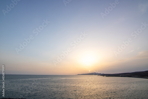 Sunset with a sea view on a rocky coast in warm colors. Landscape at the stony beach of Tarajalejo on Fuerteventura, Canary Islands, Spain.