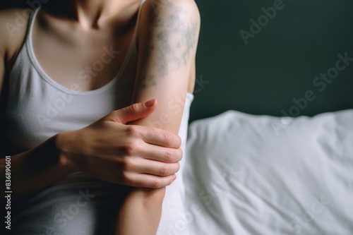Cropped shot of young woman suffering from skin allergy, scratching her forearm with fingers photo