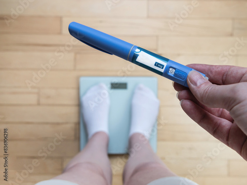  Ozempic Insulin injection pen for diabetics and weight loss. Woman weighs herself and holds Ozempic in her hand. photo