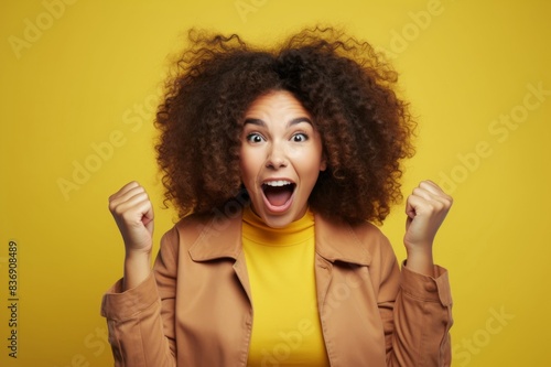 studio shot of an attractive young woman looking excited against a yellow background