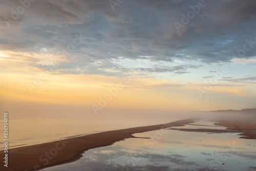 Empty sandy beach of Baltic sea covered with fog after rain during the sunset at summer