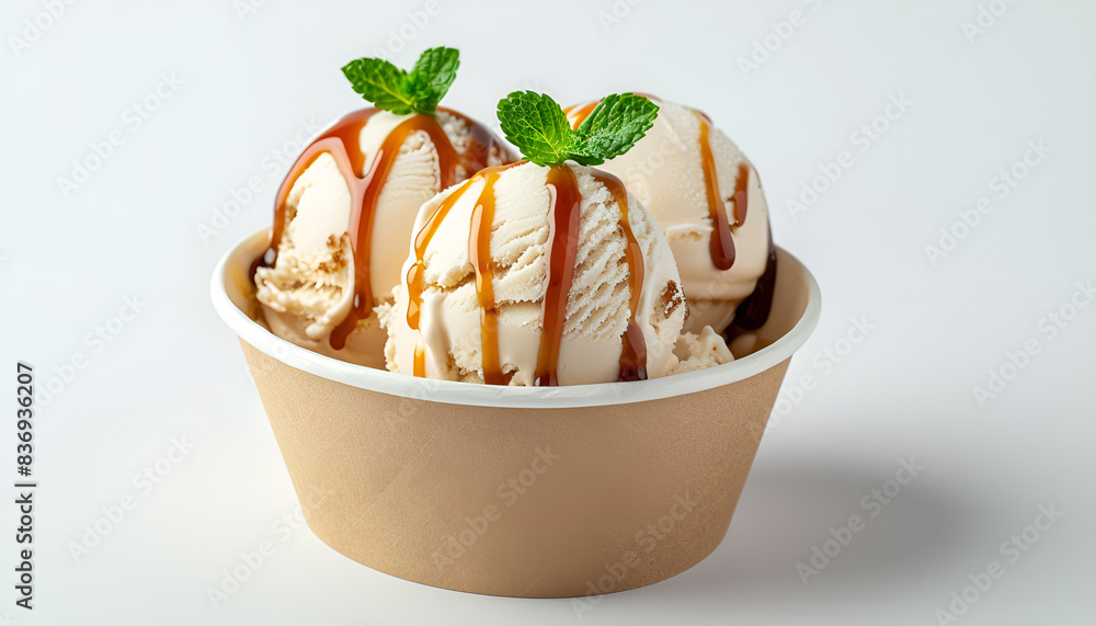 Scoops of delicious ice cream with caramel sauce and mint in paper cup isolated on white Scoops of delicious ice cream with caramel sauce and mint in paper cup isolated on white