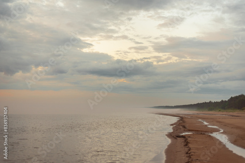 Empty sandy beach of Baltic sea covered with fog after rain during the sunset at summer