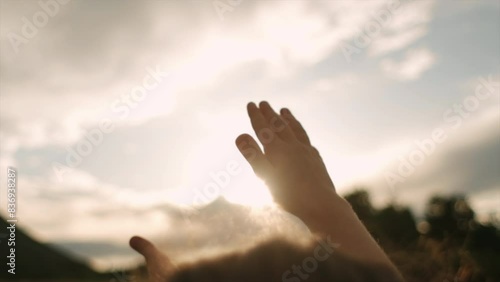 Hands of preteen girl reaches for sunset and beautiful sky. Sun between fingers of kids hand in park. Little child stretches her hand to sun, dreams in nature. Child plays with sun. Happy childhood
