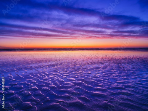 Seascape during sunrise. Long exposure. Bright clouds on the sky. Lines of sand on the seashore. Bright sky during sunset. A sandy beach at low tide. Wallpaper and background.