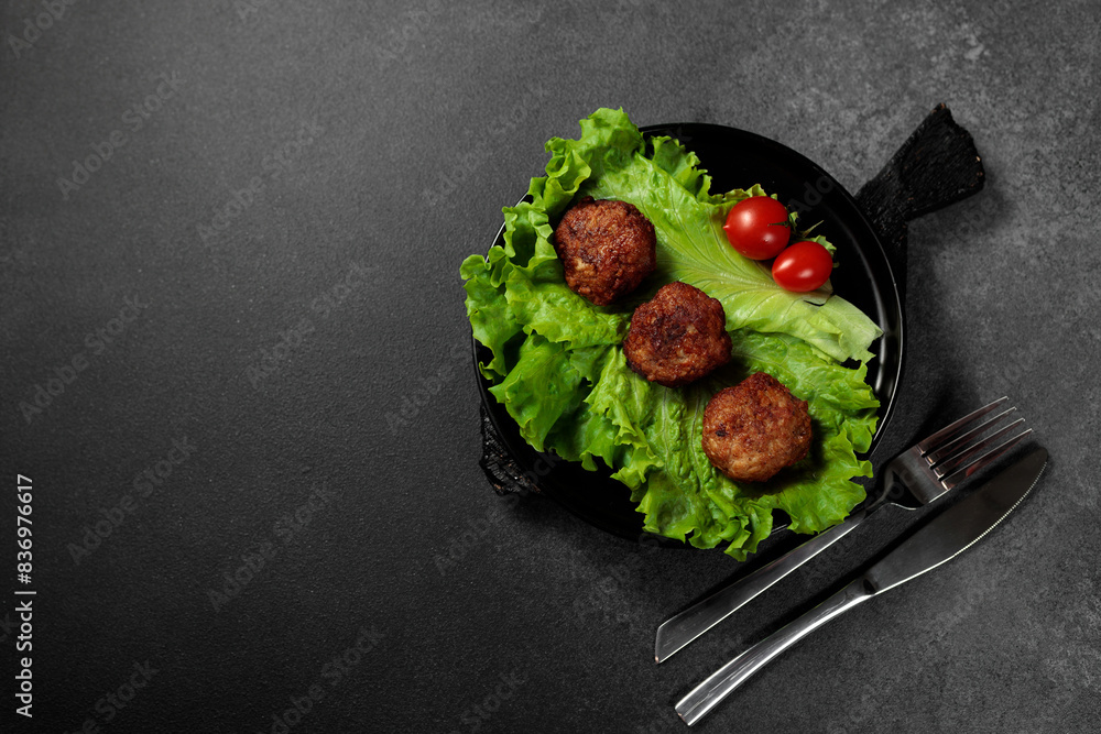 Fried cutlets on a lettuce leaf with tomato on a black background Fried cutlets on a lettuce leaf with tomato on a black background