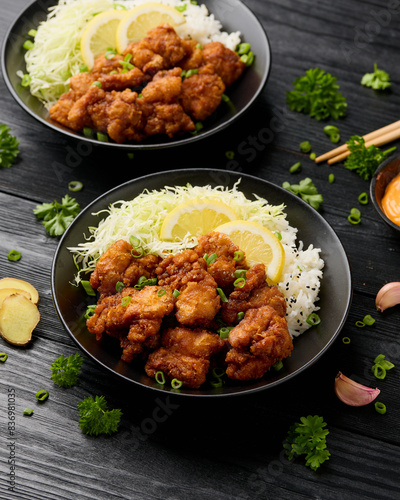 Fotografie Japanese Fried crispy Chicken Karaage in black bowl with rice and cabbage
