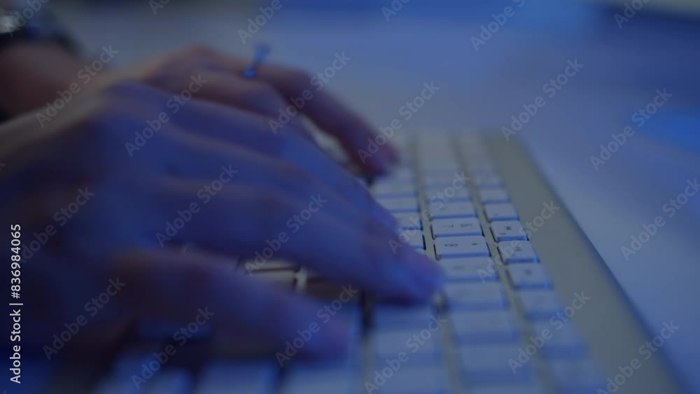 Close up of hands of unrecognizable hacker or workaholic typing on wireless keyboard in neon light Close up of hands of unrecognizable hacker or workaholic typing on wireless keyboard in neon light