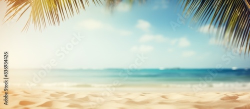 Blurry palm tree and tropical beach background with sandy surface, emphasizing a summer vacation and travel theme. Ample copy space for adding text or images.