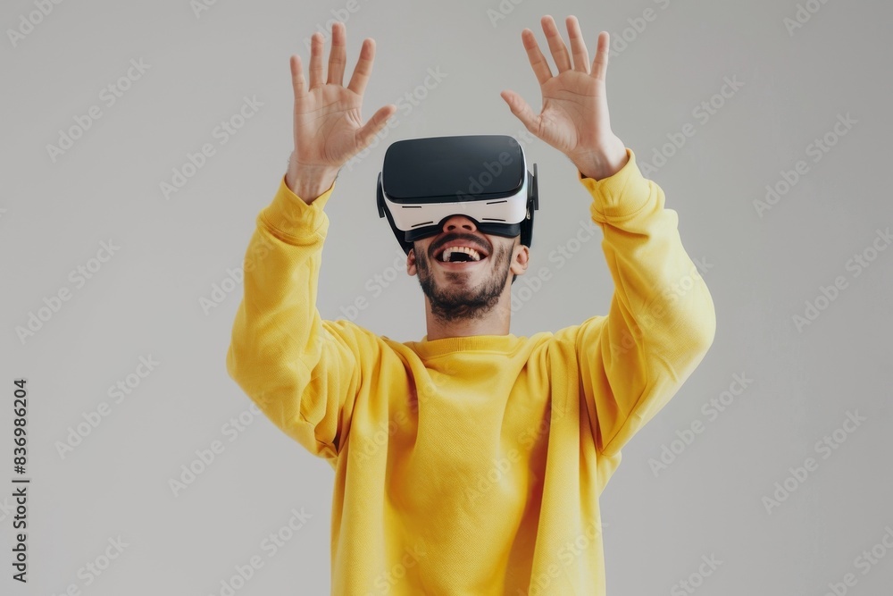 Naklejka premium A man wearing VR glasses is smiling and standing with his hands raised