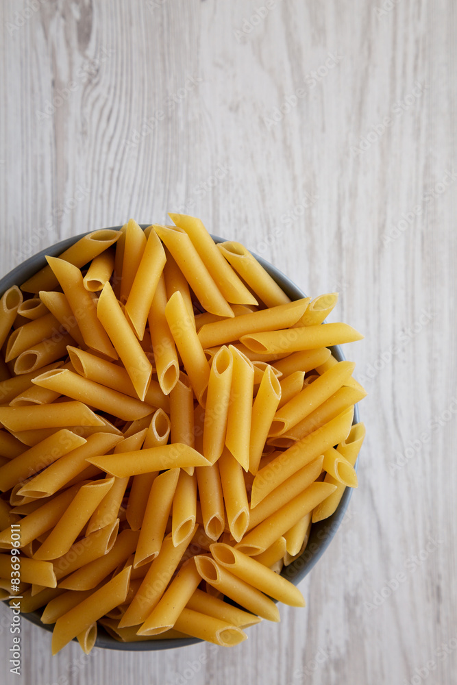 Raw Organic Dry Penne Pasta in a Bowl, top view. Overhead, flat lay, from above. Space for text. Raw Organic Dry Penne Pasta in a Bowl, top view. Overhead, flat lay, from above. Space for text.