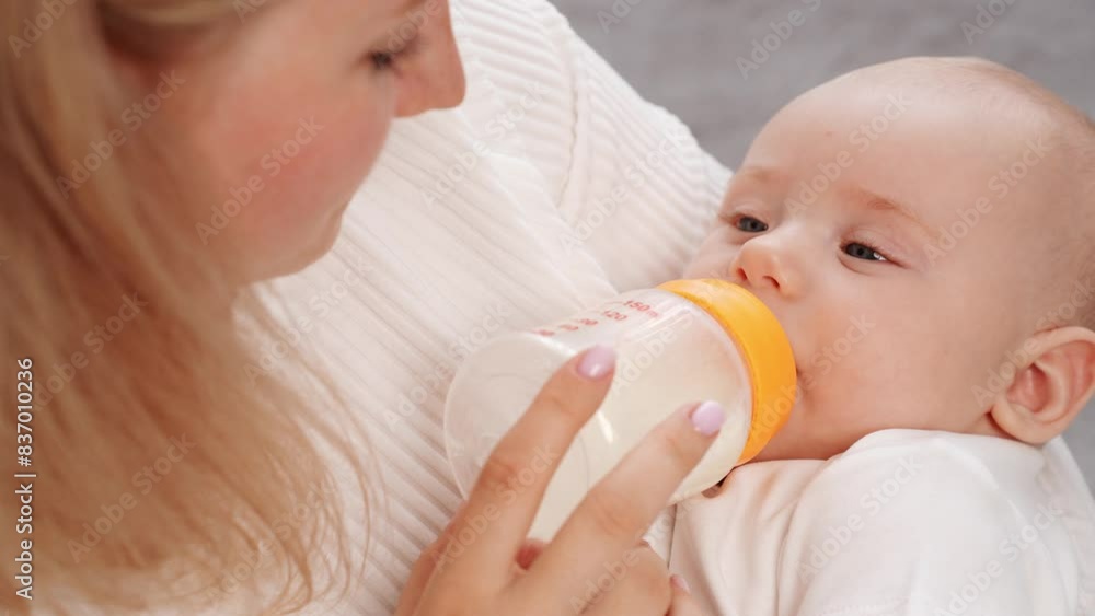 Woman bottle feeds small newborn with formula as alternative to breastfeeding, close-up. Mom takes care of child. Concept of child care, maternity leave, infancy, infant nutrition, professional nanny Woman bottle feeds small newborn with formula as alternative to breastfeeding, close-up. Mom takes care of child. Concept of child care, maternity leave, infancy, infant nutrition, professional nanny