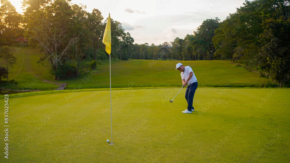 Obraz premium Blurred golfer playing golf in the evening golf course, on sun set evening time.