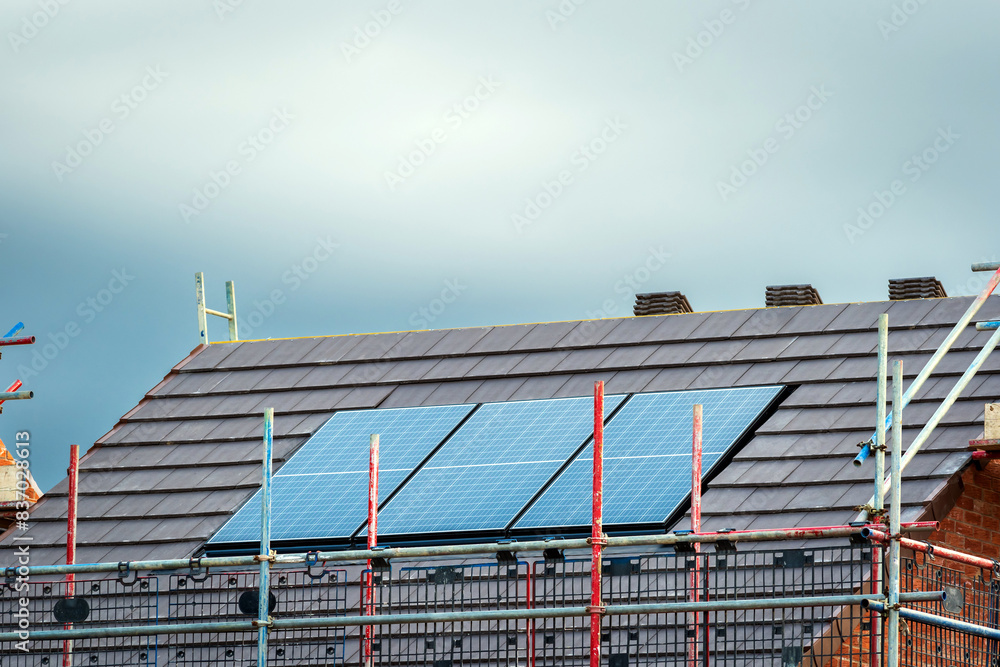 Photovoltaic solar panels on the roof of new built house in england uk. The concept of a sustainable environment, construction Photovoltaic solar panels on the roof of new built house in england uk. The concept of a sustainable environment, construction