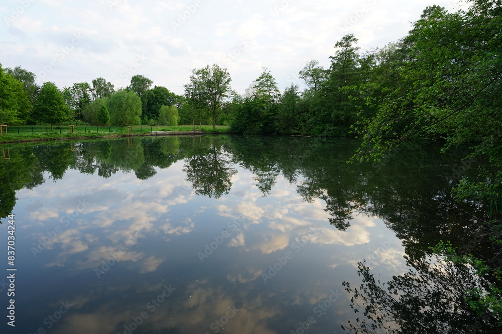 Ein Park in Bielefeld. Dies ist der Ölteich in Bielefeld, er gehört zu den Parkanlagen in Bielefeld. Im Wasser spiegelt sich die landschaft, Bäume.