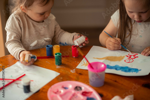 two sisters paint with paints, one is 1 year old and the older one is 5 years old. photo