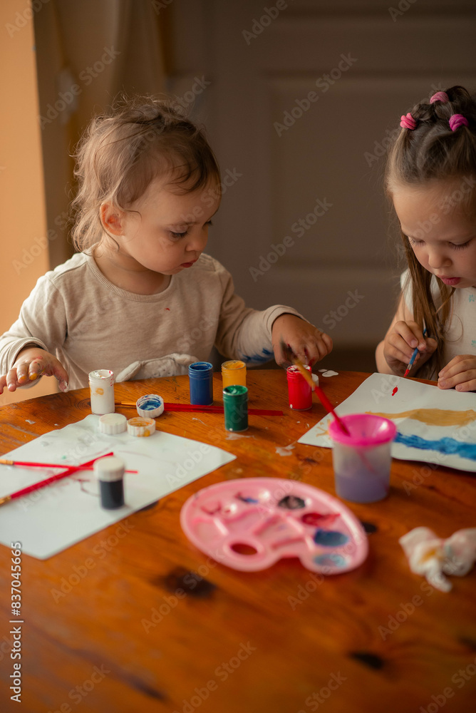 two sisters paint with paints, one is 1 year old and the older one is 5 years old. two sisters paint with paints, one is 1 year old and the older one is 5 years old.