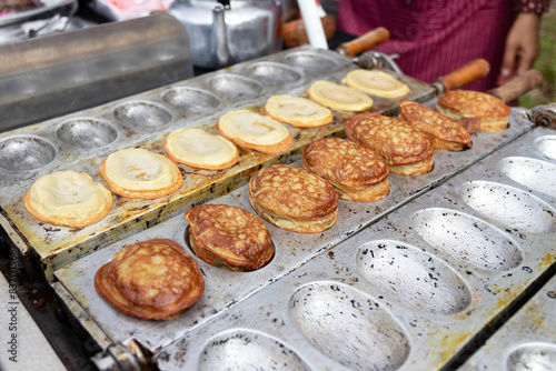 A street food vendor is cooking a traditional Korean snack called Bungeo-ppang, which is a fish-shaped pastry filled with red bean paste.