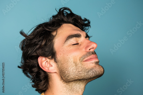 A close up of a man with beard and closed eyes looking to a side