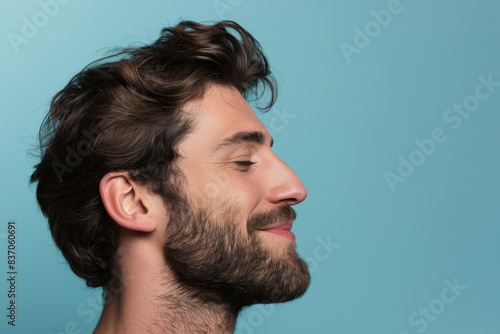 A close up of a man with beard and closed eyes looking to a side