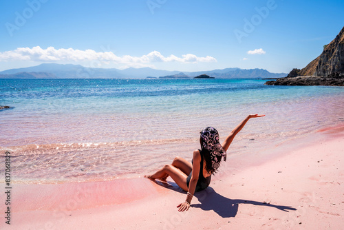 Young female tourism enjoying the tropical pink sandy beach with clear turquoise water at Komodo islands in Indonesia photo