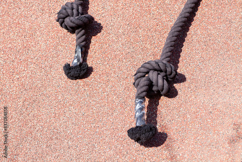 Ropes with handles on a climbing structure in a playground under bright sunlight.