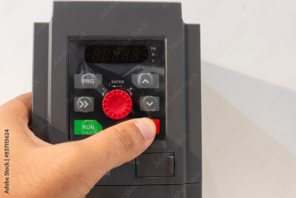 Close-up of a hand adjusting settings on an inverter variable speed drive. Perfect for concepts of technology, control, automation, and engineering. Close-up of a hand adjusting settings on an inverter variable speed drive. Perfect for concepts of technology, control, automation, and engineering.