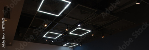 Black exposed ceiling with modern square led light industrial style metal frame grating and security camera