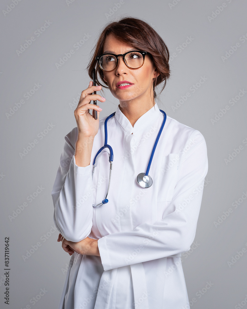 Female doctor with cellphone studio portrait against isolated background Female doctor with cellphone studio portrait against isolated background