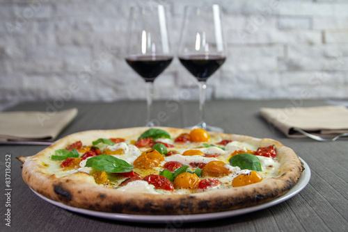 pizza con datterino rosso e datterino giallo con calici di vino rosso