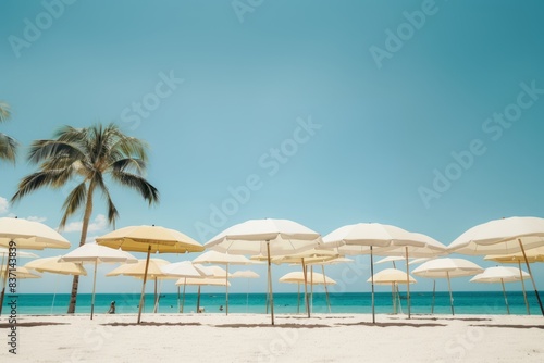 White umbrellas with palm trees on the beach and a clear blue sky.