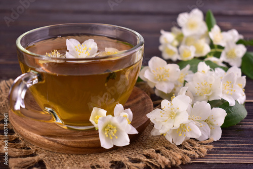 A cup of jasmine tea and fresh jasmine flowers on a dark background. 