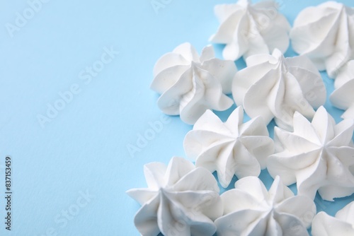 Tasty meringue cookies on light blue background  closeup. Space for text