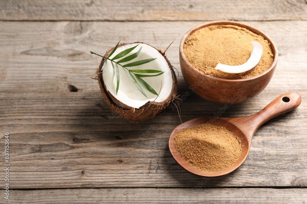 Coconut sugar in bowl, spoon, fruit and palm leaves on wooden table, closeup. Space for text Coconut sugar in bowl, spoon, fruit and palm leaves on wooden table, closeup. Space for text