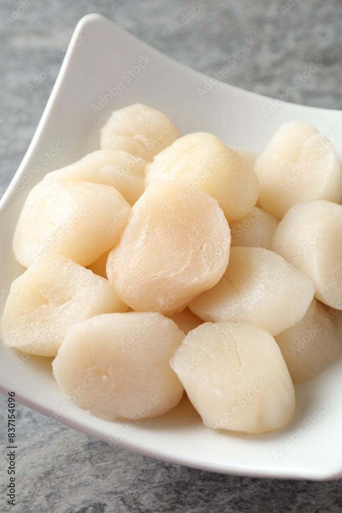 Fresh raw scallops in bowl on grey table, closeup Fresh raw scallops in bowl on grey table, closeup