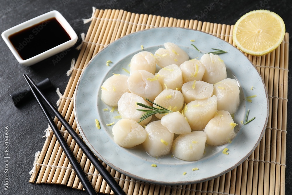 Raw scallops with lemon, rosemary and soy sauce on dark textured table, closeup Raw scallops with lemon, rosemary and soy sauce on dark textured table, closeup