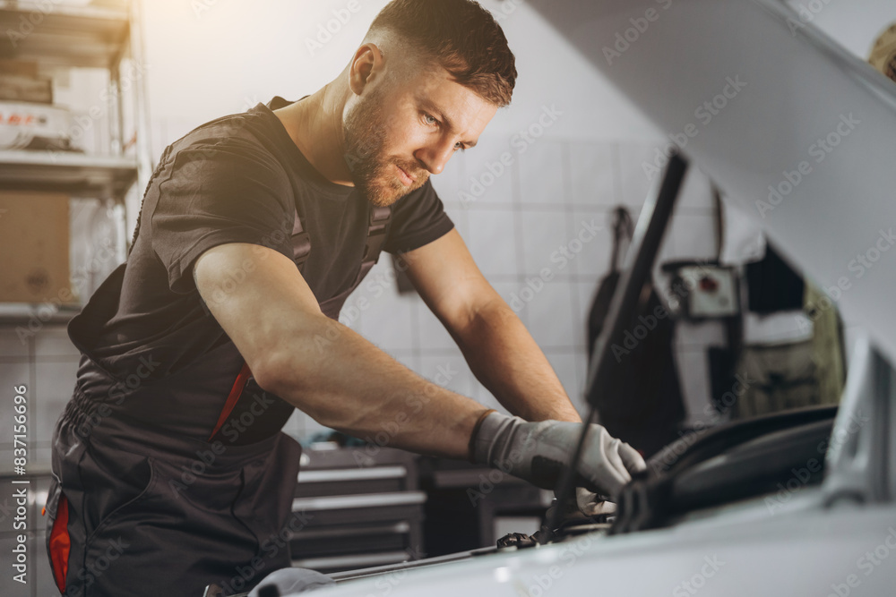 Car service, repair, maintenance and people concept - car mechanic man with lamp working at workshop Car service, repair, maintenance and people concept - car mechanic man with lamp working at workshop