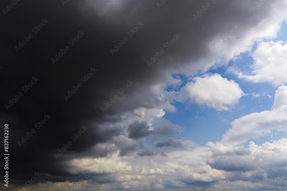 Obraz premium Epic Dramatic storm dark grey cumulus rain clouds against blue sky background texture, thunderstorm