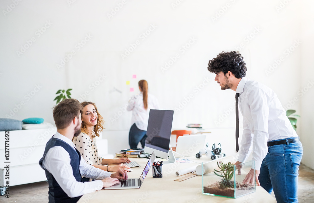 Young group of colleagues working on a new project together in a startup company office. Working in co-working space. Young group of colleagues working on a new project together in a startup company office. Working in co-working space.