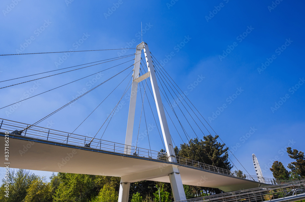 construction of a modern cable-stayed bridge on background of blue sky in Anhor Park in Tashkent in Uzbekistan. Uzbek new pedestrian suspension bridge construction of a modern cable-stayed bridge on background of blue sky in Anhor Park in Tashkent in Uzbekistan. Uzbek new pedestrian suspension bridge
