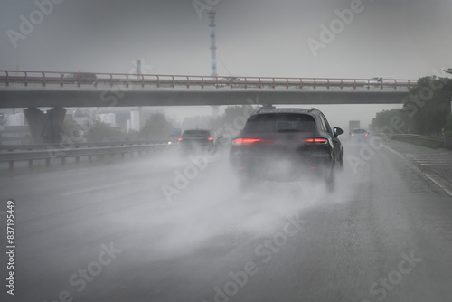 Cars driving too fast in heavy rain on wet roads with poor visibility and the risk of aquaplaning on the highway, dangerous weather for traffic and transportation, copy space, selected focus